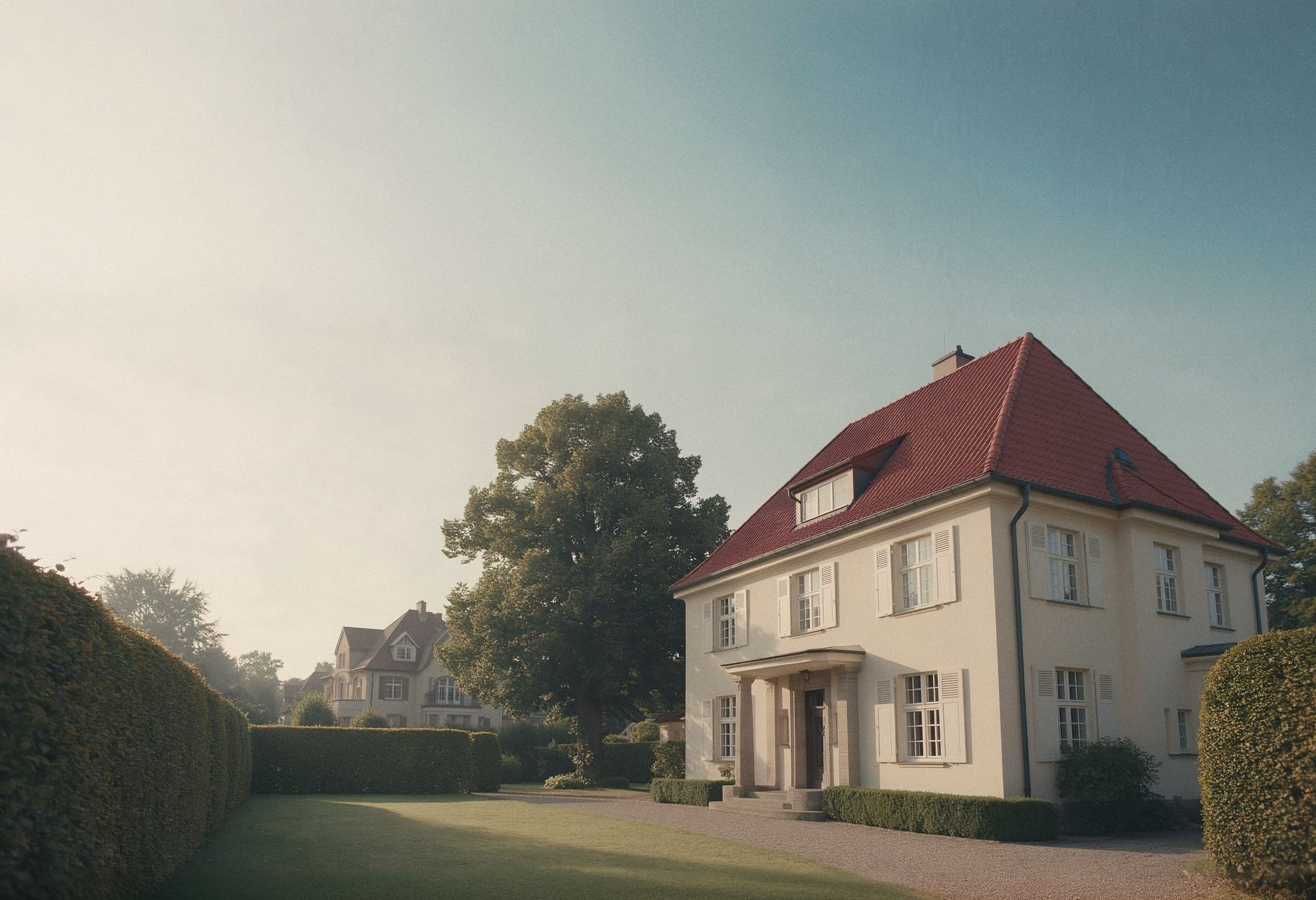 Gepflegtes Siedlungshaus aus den zwanziger Jahren mit Hecke und altem Baum